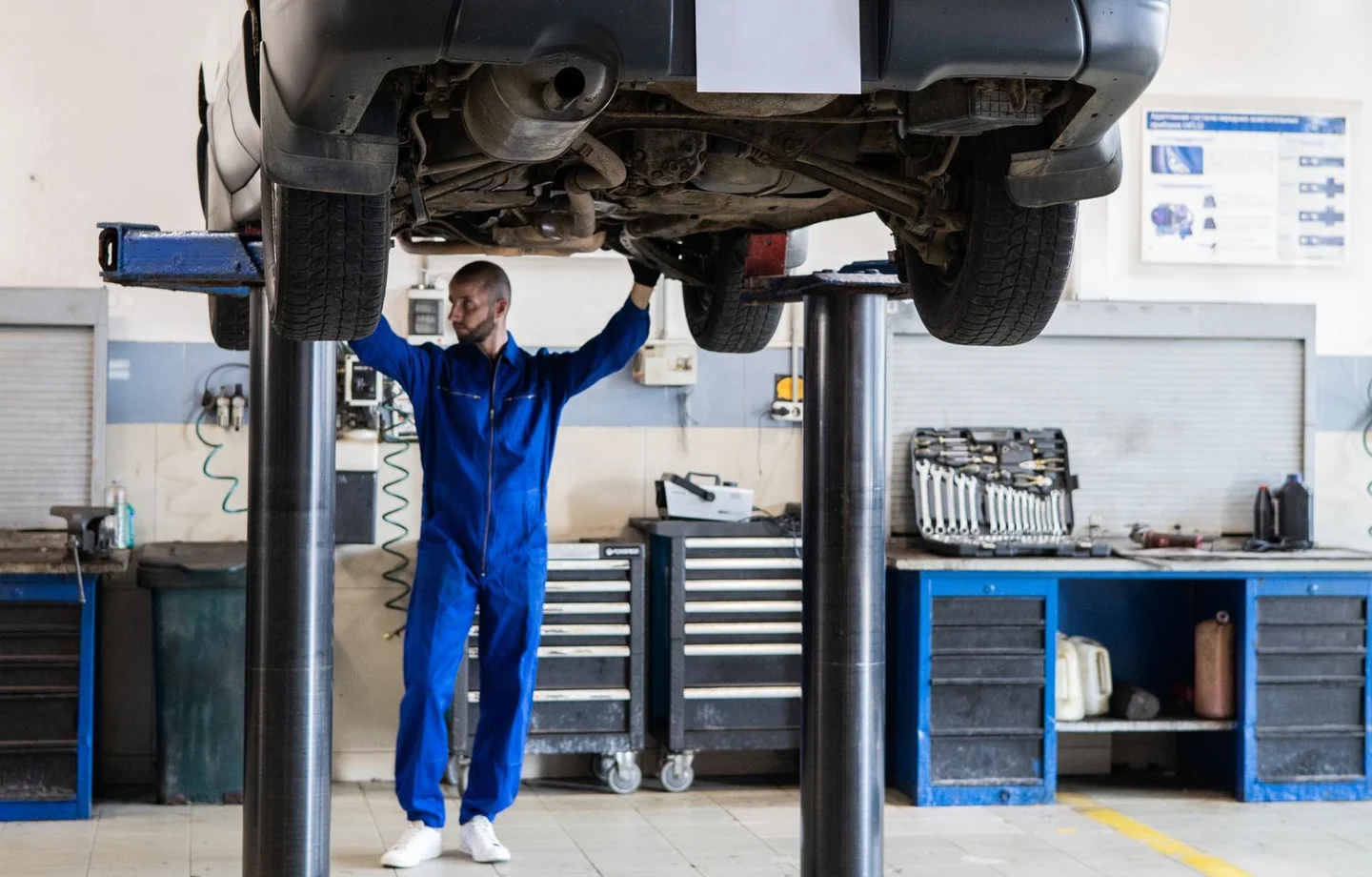 Technician inspecting vehicle underbody components