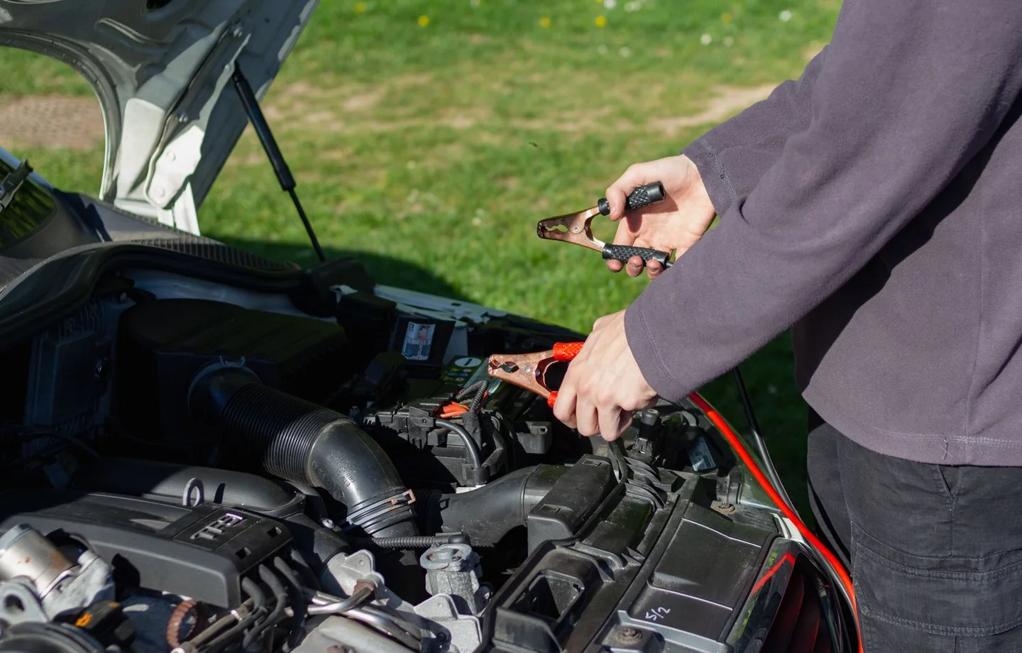 Mechanic using jumper cables at an engine bay